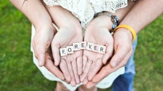 FOREVERと書かれたパズルを手のひらに乗せているカップルの手元の画像
