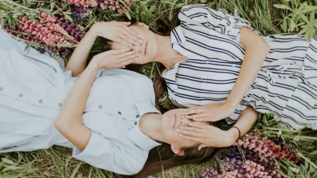 二人の姉妹が草原に寝転んでいる画像