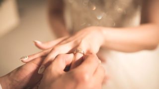 新婦の指に指輪をはめる新郎の画像
