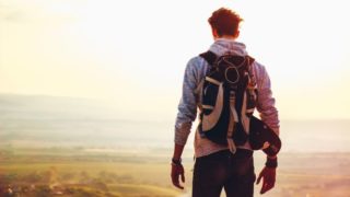 山の頂から風景を望む男性の後ろ姿